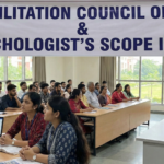 A wide-angle photograph of an academic seminar room filled with attendees listening to a speaker at a podium. A large white banner hangs in the background with blue text reading "REHABILITATION COUNCIL OF INDIA & A PSYCHOLOGIST'S SCOPE IN INDIA".