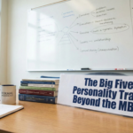 A professional psychology workspace featuring a sign reading "The Big Five Personality Traits: Beyond the MBTI." The scene includes a wooden desk with a stack of academic journals, an open notebook, a coffee mug with the "Formal Psychology" logo, and a whiteboard in the background displaying personality trait diagrams.