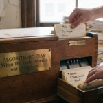 A vintage wooden card sorting machine labeled "Algorithmic Bias." It sorts index cards into "Preferred" and "Secondary" slots based on labels like "Male," "Ivy League," "Female," and "State School," symbolizing systemic prejudice in code.